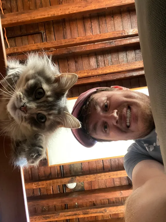 Edward grinning next to Tecate, a fluffy grey and white cat looking straight at the camera